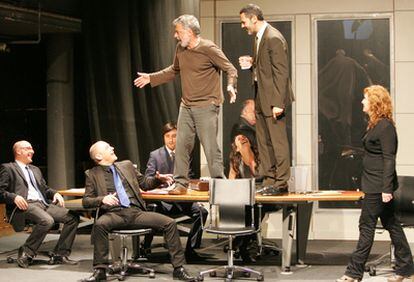 Adolfo Fernández (a la izquierda) y el actor Roberto Enriquez sobre la mesa, rodeados del equipo de la obra 19.30, en un ensayo.