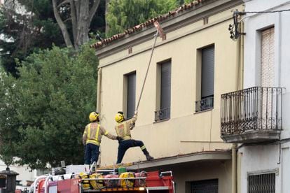 Dos bomberos retiran las tejas dañadas de una vivienda como consecuencia de la tormenta en La Bisbal.
