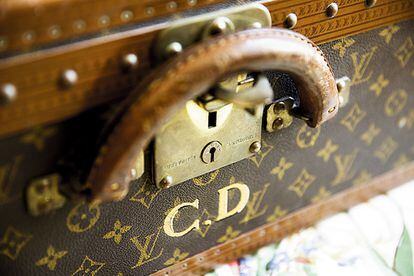 Una maleta de Louis Vuitton con las iniciales del maestro y la invitación a la inauguración.