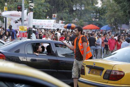 Un voluntario dirige en tráfico, desde un montículo destrozado por los disturbios, en una abarrotada plaza Sintagma de Atenas.