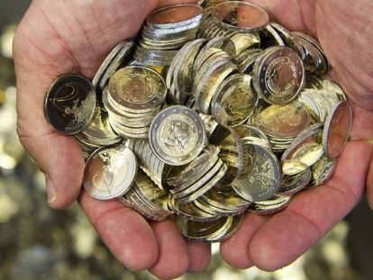 Un hombre sostiene varias monedas de euro. EFE/Archivo