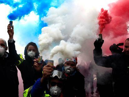 Conductores de ambulancia franceses sostienen bombas de humo azules, blancas y rojas, formando los colores de la bandera francesa, durante una manifestación en la Plaza de la Concordia, en París.
