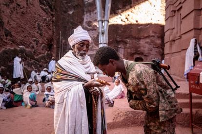 Un miliciano amhara aliado del Ejército etíope besa una cruz sostenida por un cura ortodoxo en Lalibela tras la recuperación de esta ciudad por el Gobierno federal.