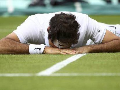 Federer, tendido sobre el c&eacute;sped de la pista central de Wimbledon.