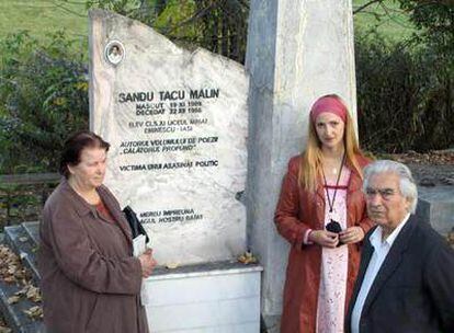 Ana, Alina y Alexander Tacu frente a la lápida de su hijo, Malin, en el cementerio de Iasi.