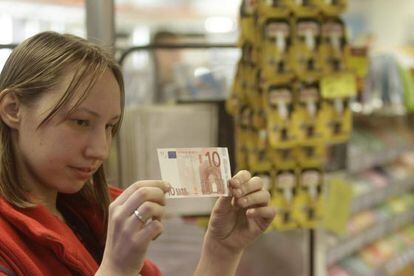 Una cajera, con un billete de 10 euros en un supermercado en Riga.