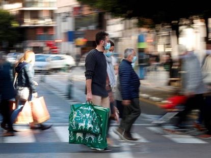 Varias personas cargan con sus bolsas en una calle de Valencia tras realizar sus compras navideñas el pasado mes de diciembre.