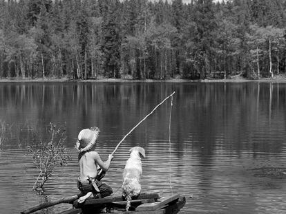 Un chico, ataviado al estilo de Huckleberry Finn, pesca en un lago.