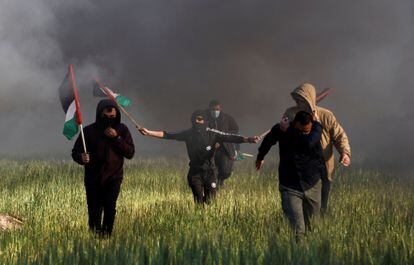 Cinco palestinos corren mientras se enfrentan a las fuerzas israelíes, cerca de la frontera, este miércoles. 