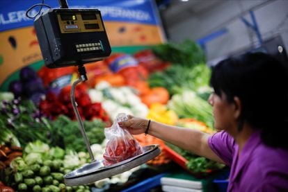 Una vendedora de vegetales pesa tomates en un mercado en Buenos Aires, el pasado 14 de marzo.