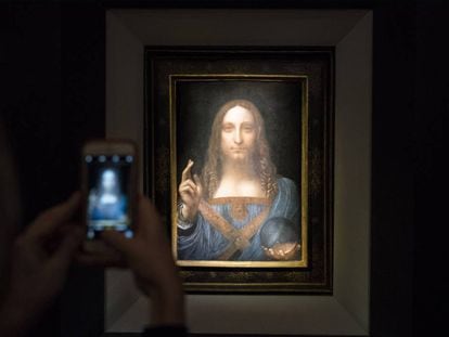 Un visitante toma una foto del Salvador Mundi en Christie&#039;s.