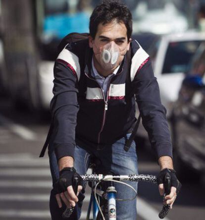 Un ciclista con mascarilla circulando hoy por las calles de Madrid.