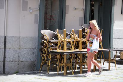 Una mujer pasa junto a una terraza de un restaurante de la Plaza Mayor cerrada durante la fase 0 de la desescalada.