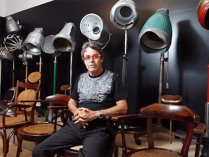 Raffel Pages sentado junto a algunos de los secadores de casco eléctricos de su colección.