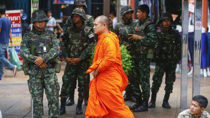 Un monje budista pasa delante de unos soldados tailandeses hacen guardia en los alrededores del monumento de la Victoria en Bangkok.
