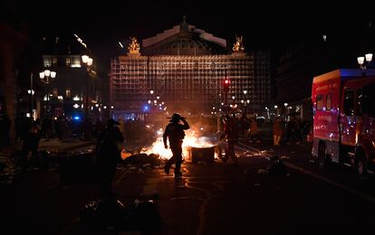 Un policía y un bombero, ante un contenedor en llamas el lunes en París.