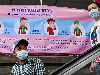 Personas con mascarillas delante de un cartel sobre el coronavirus en Bangkok el 1 de febrero. En vídeo, Filipinas registra la primera muerte por coronavirus fuera de China.