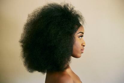 Una mujer con el pelo afro posa para una fotografía.