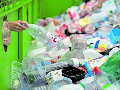 Una persona deposita envases de plástico en un contenedor para su reciclaje.