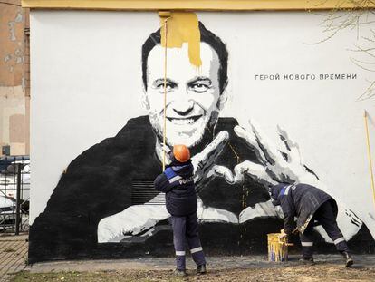 Trabajadores municipales quitan un grafiti del líder opositor ruso Alexéi Navalni, en el que se puede leer "héroe de nuestro tiempo", en San Petersburgo, el 28 de abril de 2021.