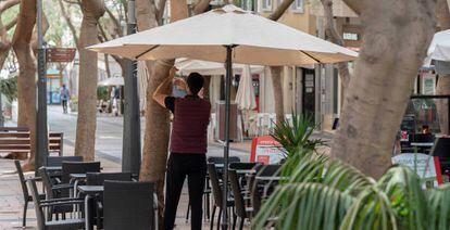 Un camarero coloca una sombrilla en la terraza de un bar en Santa Cruz de Tenerife. 