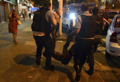 Dos policías trasladan a un hombre herido durante los enfrentamientos tras la muerte de un adolescente en la la favela de Pavao-Pavaozinho.