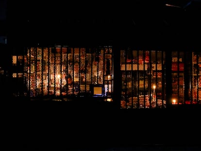 El dueño de una tienda espera a los clientes, iluminado por una vela, durante un apagón en Soweto, Sudáfrica.