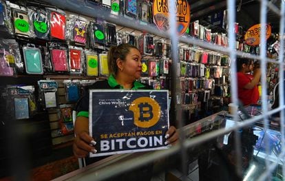 Una vendedora sostiene un cartel de pago con bitcoin en El Salvador.