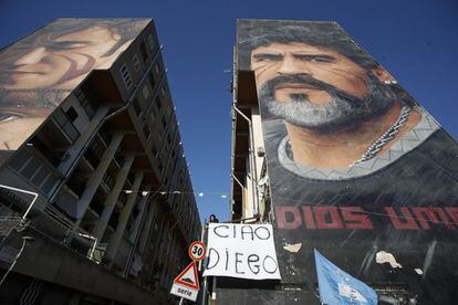 Una mujer coloca un cartel tras la muerte de Maradona en un edificio de Nápoles (Italia), este jueves.