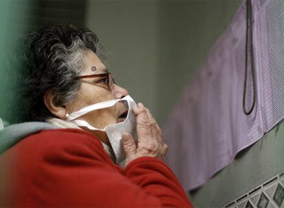 Una mujer con la mascarilla para evitar el contagio de la nueva gripe consulta el padrón electoral en una escuela de Argentina