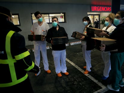Personal sanitario del Hospital Madrid Sanchinarro recoge unas pizzas a la entrada de Urgencias.