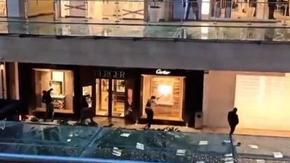 Three individuals break the windows of the Berger jewelry store while another watches, in a screenshot of a video posted on social networks.
