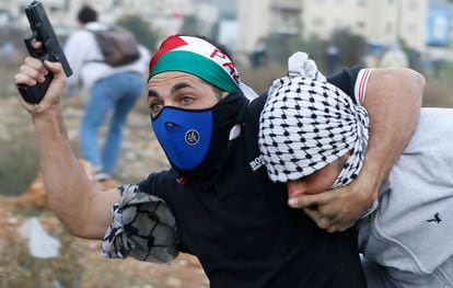 Un agente encubierto israel&iacute; armado detiene a un manifestante palestino en Ramala.
