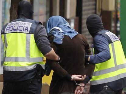 Dos policías acompañan a un detenido en el barrio de Vallecas (Madrid).