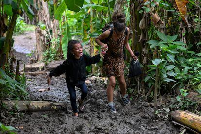 A Venezuelan migrant girl is helped by her mother as they arrive at Canaan Membrillo village, the first border control of the Darien Province in Panama, on October 13, 2022. - The clandestine journey through the Darien Gap usually lasts five or six days at the mercy of all kinds of bad weather: snakes, swamps and drug traffickers who use these routes to take cocaine to Central America. (Photo by Luis ACOSTA / AFP) / TO GO WITH AFP STORY BY JUAN JOSE RODRIGUEZ