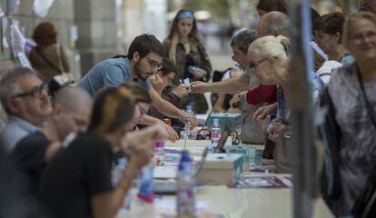 Varios jóvenes universitarios informan con ordenadores y teléfonos móviles a personas mayores del lugar donde les correspondía.