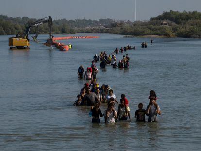 Una caravana pasa junto a una serie de boyas, que se construyen para disuadir a los migrantes de cruzar el río Grande, Texas en Estados Unidos.