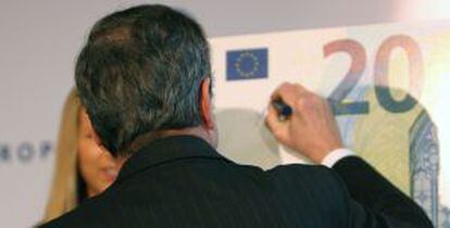 El president del BCE, Mario Draghi, firma en una rèplica del nou bitllet.