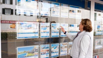 Una mujer mira anuncios de casas en una inmobiliaria de Menorca.
