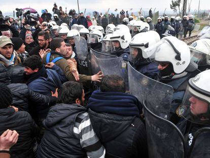 Migrantes ante una barrera policial, este domingo en Idomeni.