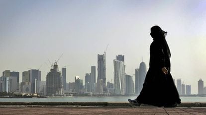 Una mujer camina frente a los rascacielos de Doha, Qatar.