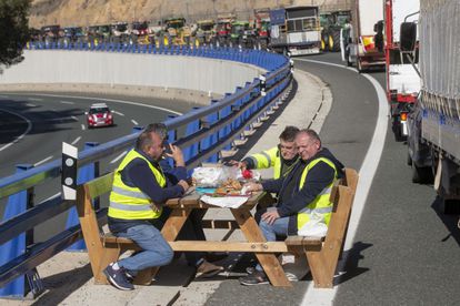 Varios agricultores almuerzan este miércoles mientras sus tractores bloquean en la A-30 el puerto de la Cadena, en la Región de Murcia.
