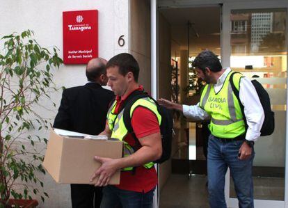 Agentes con documentaci&oacute;n saliendo de Servicios Sociales.