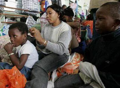 Una inmigrante arregla el cabello de su hijo durante la ocupación de un pabellón deportivo cercano a París por gente sin vivienda, en 2006.