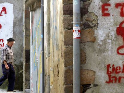 Un hombre pasa al lado de un grafiti con el logo de ETA.