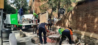 Operarios de limpieza retiran los cascotes del muro contra el que ha chocado un camión, provocando la muerte de un hombre.