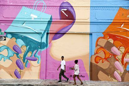 Una pareja atraviesa una pared adornada con un grafiti en el barrio de Wynwood, Miami.