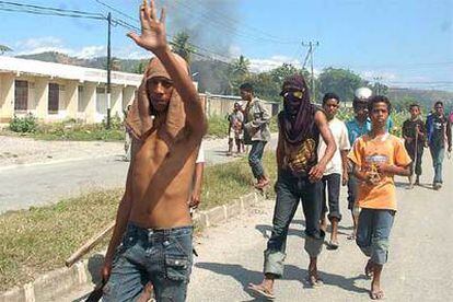Jóvenes timorenses caminan ayer por una calle de Dili durante los disturbios.