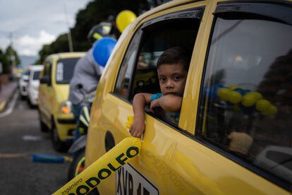 Un niño sostiene propaganda de Rodolfo Hernández mientras se asoma por la ventana de un auto.