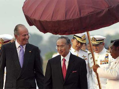 Don Juan Carlos conversa con el rey de Tailandia, Bhumibol Adulyadej, a su llegada a Bangkok.